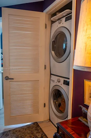 Stacked laundry appliances within a louvered door enclosure