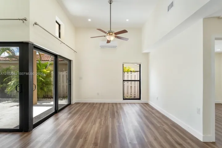Vaulted ceilings, wood-finish flooring, ceiling fan, split-unit air conditioning, and sliding glass doors