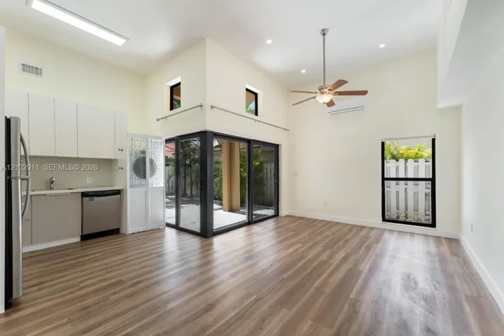 Vaulted ceilings with recessed lighting, wood-finish flooring, stainless steel appliances, modern cabinetry, and sliding glass doors