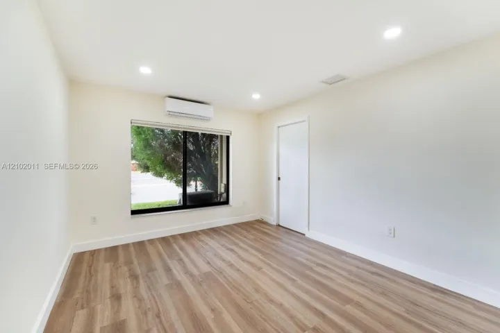 Recessed ceiling lighting, wood-finish flooring, and a mini-split air conditioning unit