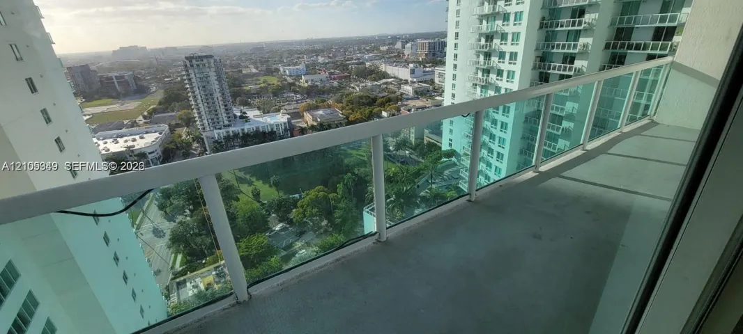 Spacious balcony with a glass and metal railing, offering panoramic urban scenery