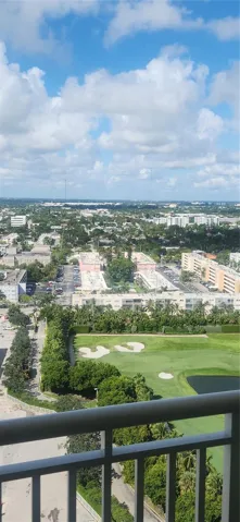 Elevated perspective of the surrounding area featuring a multi-level golf course, manicured grounds, mature trees, and urban landscape