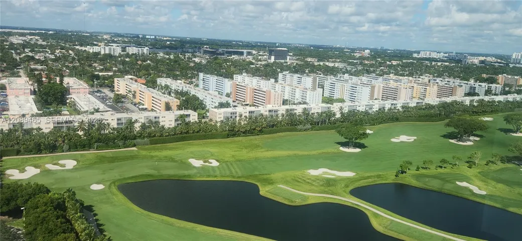 Aerial perspective featuring a sprawling golf course, multiple sand traps, expansive fairways, and integrated water features