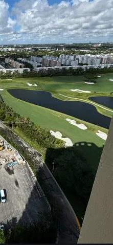 Aerial perspective featuring a golf course expanse, water hazards, sand bunkers, and mature perimeter trees