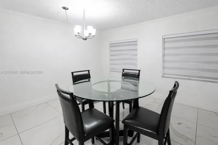 Recessed lighting, crown molding, two windows with blinds, and large format floor tile
