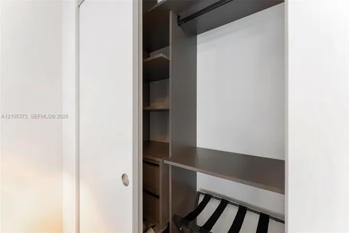 Custom closet system with integrated shelving, hanging rod, and sliding panel doors