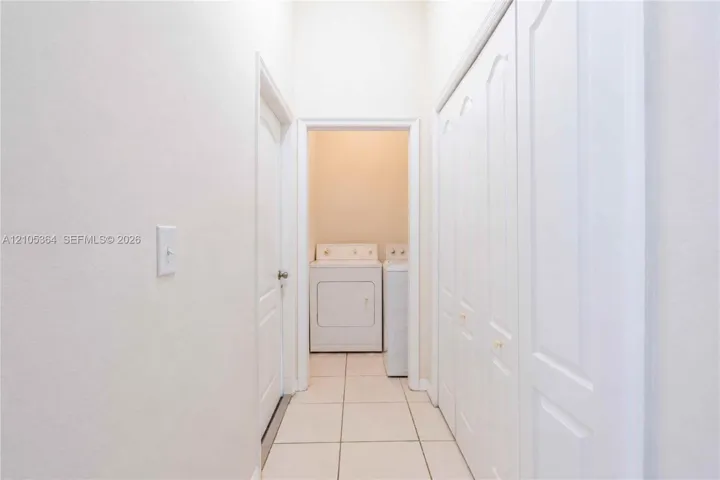 Hallway with light-colored tile flooring, white walls, and bi-fold closet doors