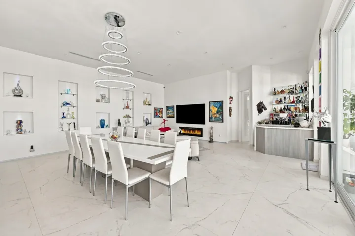 Open-concept living space with large format tile flooring, a built-in wet bar, recessed wall niches, and a linear fireplace