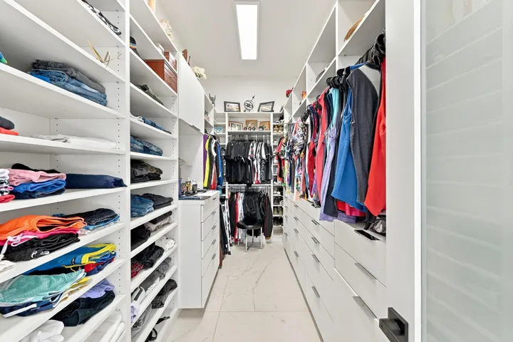 Custom closet system featuring extensive shelving, multiple hanging rods, built-in drawers, and polished flooring