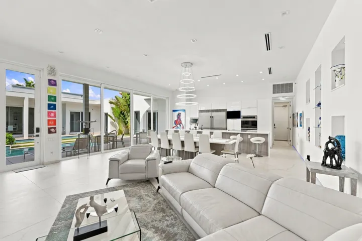 Open-concept living area with large format tile flooring, a modern kitchen featuring built-in stainless steel appliances, a kitchen island with seating, and integrated wall display niches