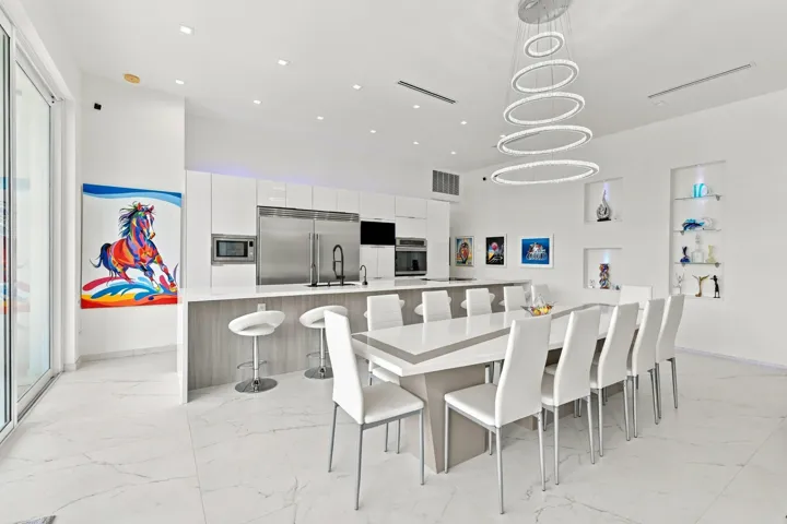 Kitchen and dining area featuring a modern chandelier, built-in display niches, stainless steel appliances, and white tile flooring