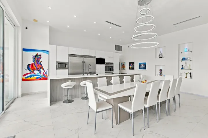 Sleek kitchen with white cabinetry and stainless steel appliances, featuring a large central island with seating
