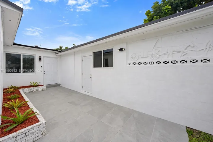 Exterior patio with large format tile, white stucco walls, windows, and decorative wall relief