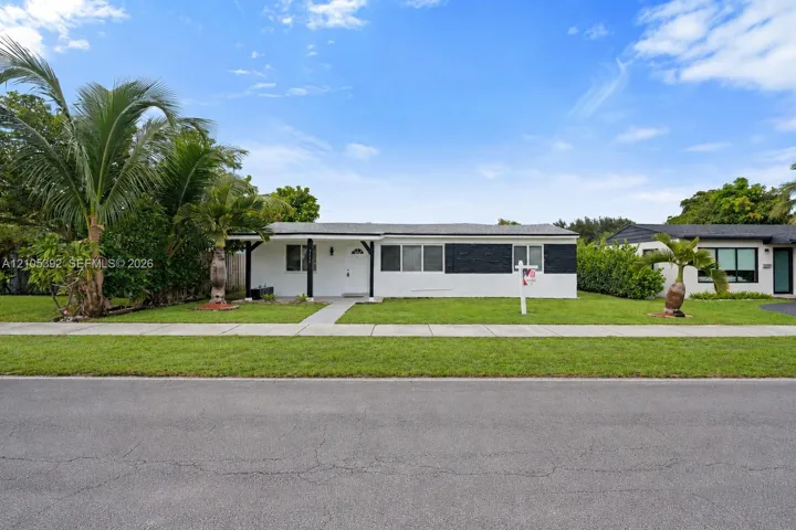 White exterior with black accents, covered entry, and a level lawn