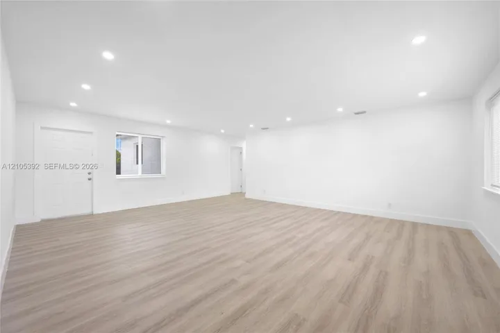 Spacious room featuring wood-finish flooring, recessed lighting, and white walls