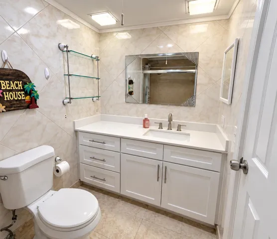 Wall-mounted tile with diagonal pattern, white vanity with ample storage, integrated sink, and glass shelving