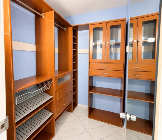 Custom closet system featuring wood-finish cabinetry, integrated shelving, and glass-front upper cabinets
