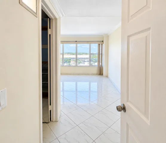 Glossy square tile flooring, expansive window, crown molding, and neutral wall tones