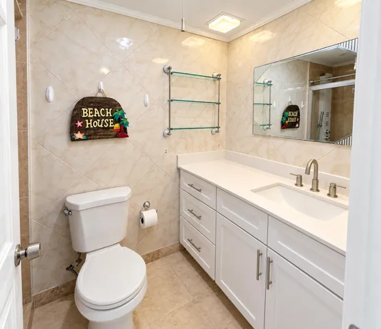 Vanity with integrated sink and chrome faucet, white cabinetry with brushed nickel hardware, wall-mounted glass shelving, and light-toned wall tiling