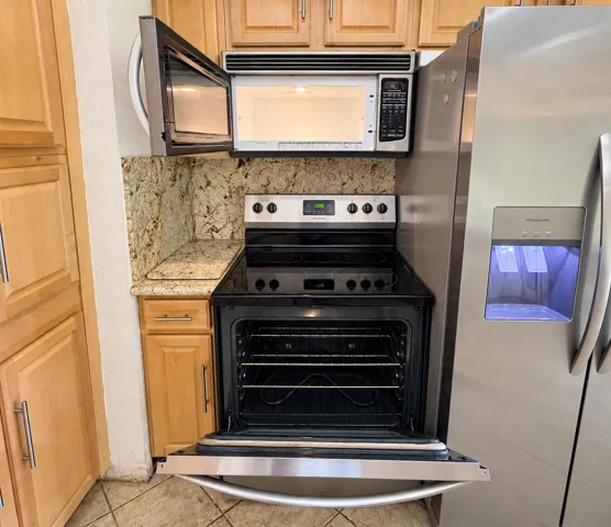 Stainless steel appliances, over-range microwave, electric range, and light wood-finish cabinetry