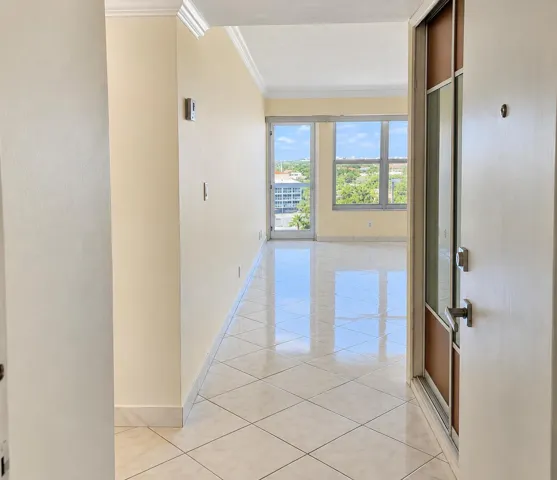Entryway with square tile flooring, crown molding, and a paneled entry door with glass inserts