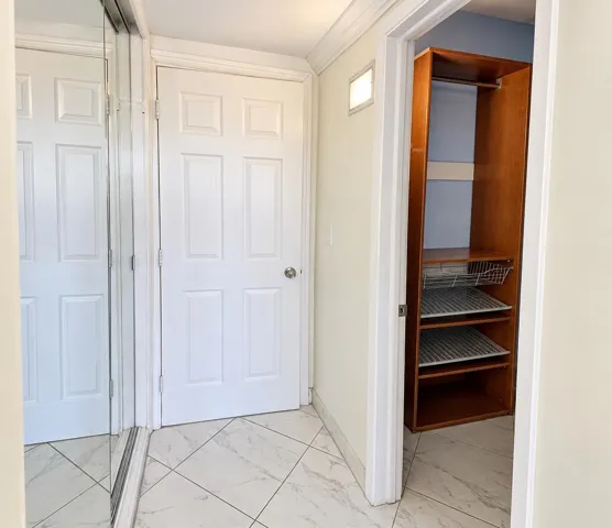 White paneled doors, mirrored closet doors, tile flooring, and a built-in closet system with shelving