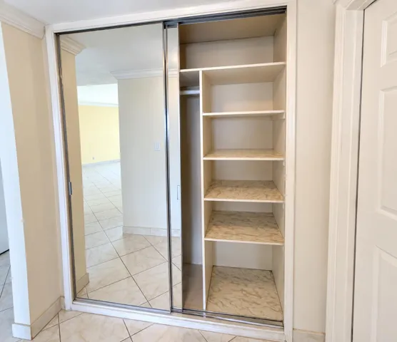 Built-in closet with mirrored sliding doors, integrated shelving, and hanging rod