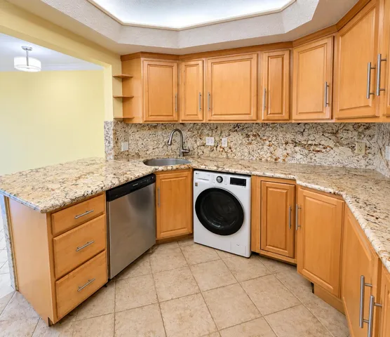 Kitchen with light wood-finish cabinetry, granite countertops, and a tile floor