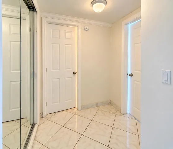 Tile flooring, six-panel interior doors, crown molding, flush mount ceiling light, mirrored closet doors