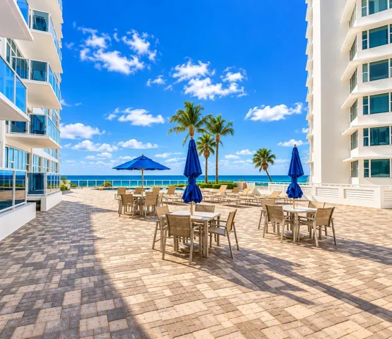 Paver patio with multiple seating areas, surrounded by modern architecture and palm trees