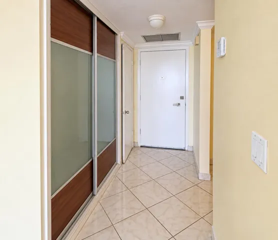 Tiled flooring, crown molding, and sliding closet doors with frosted glass panels and wood-finish accents