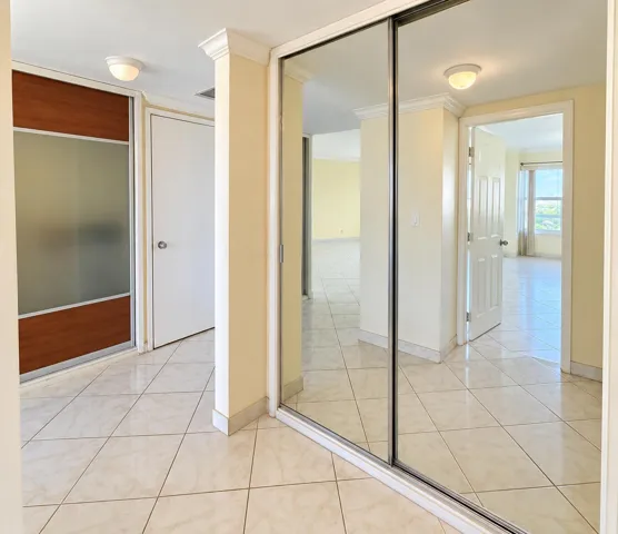 Mirrored closet doors, tiled flooring, wood-finish closet doors, crown molding, flush mount lighting