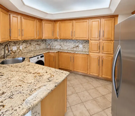 Extensive cabinetry, granite countertops, tile flooring, stainless steel appliances, and a built-in sink