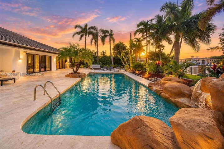 Expansive outdoor area featuring a swimming pool, rock waterfall, and integrated lighting