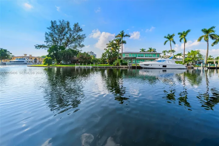 Waterfront property with private boat dockage, mature palm trees, and manicured lawn