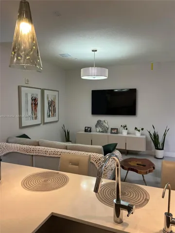 Integrated living space with a kitchen island, contemporary pendant lighting, recessed ceiling lights, wall-mounted television, and a built-in media console