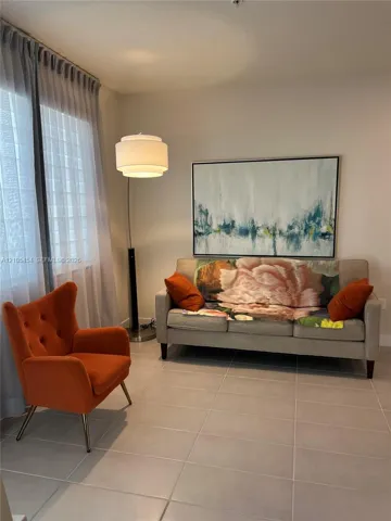 Light-colored wall finishes, full-height window with sheer drapes, recessed ceiling light, tile flooring, and a contemporary floor lamp