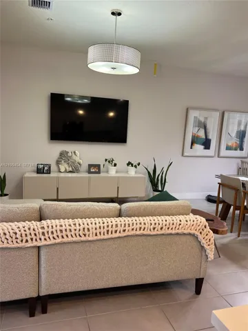 Vaulted ceiling with a contemporary drum pendant light fixture, wall-mounted television, and a floating console cabinet