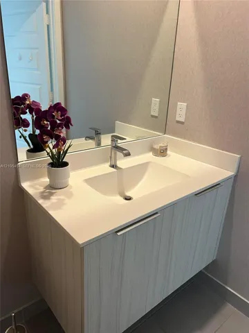 Floating vanity with light wood-finish cabinetry, integrated rectangular sink, and polished chrome faucet