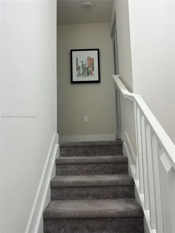 Staircase with gray carpeting and white handrails