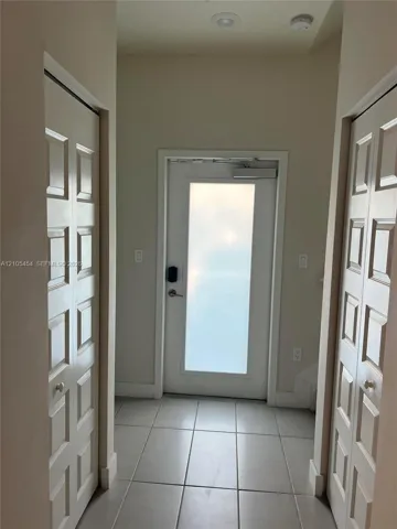 Entryway featuring tile flooring, a frosted glass panel door with a smart lock, and recessed ceiling lighting