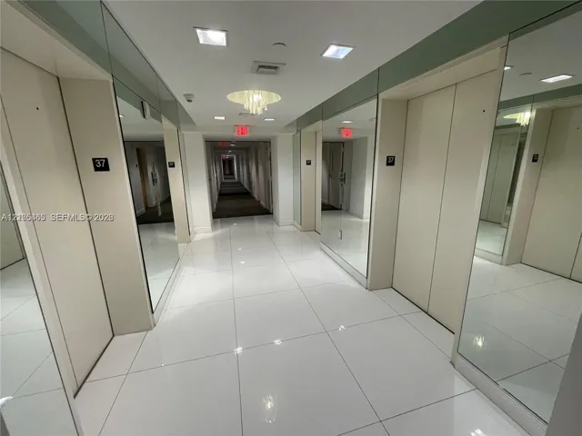Polished tile flooring, recessed ceiling lighting, decorative ceiling fixture, mirrored wall panels, and light-toned walls