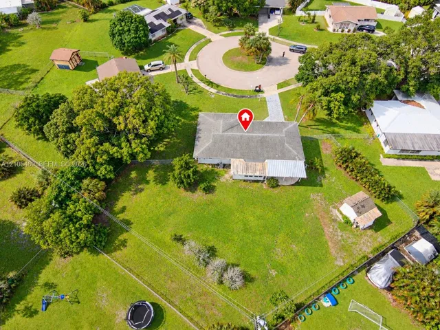 Expansive property featuring a circular driveway, mature trees, and a cul-de-sac street