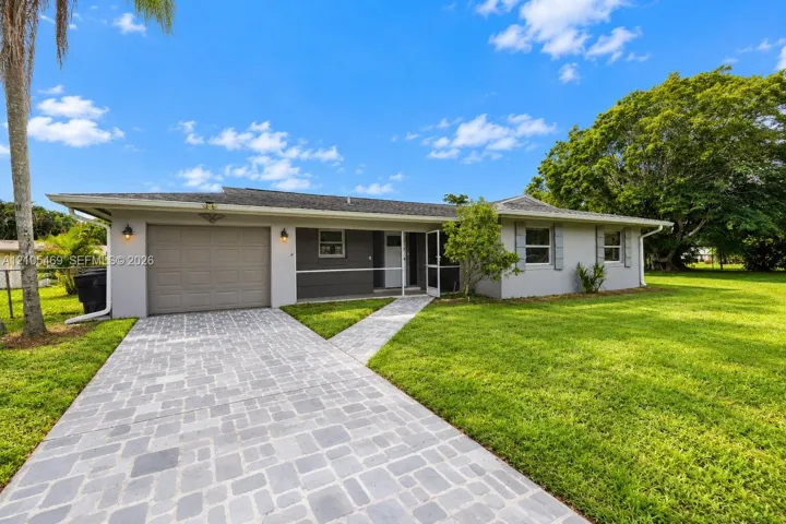 Exterior featuring a paved driveway, a separate paved walkway, a two-car garage, and established landscaping