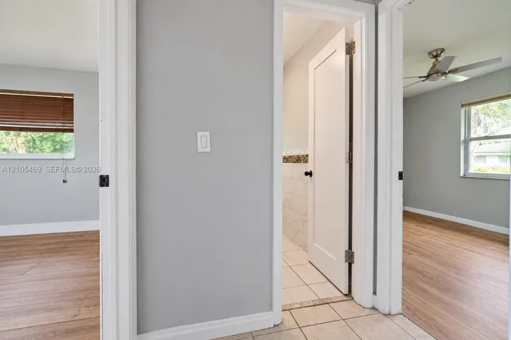 Neutral wall paint, wood-finish flooring, white trim, and tiled bathroom flooring