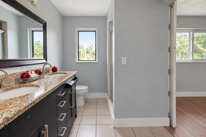 Dual vanity with stone countertop, undermount sinks, and dark cabinetry