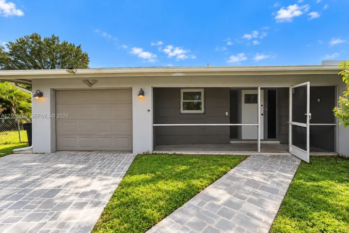 Paver driveway and walkway, attached garage, covered entryway, and exterior lighting fixtures
