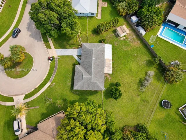 Expansive property featuring a grey shingle roof, green lawn, and concrete driveway