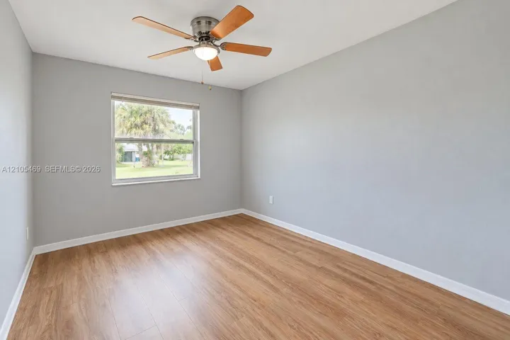 Recessed window, wood-finish flooring, ceiling fan with integrated lighting, neutral wall paint, white trim