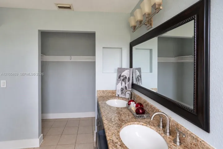 Dual undermount sinks with brushed nickel faucets, granite-style countertop, and a dark wood-framed mirror